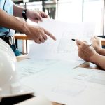 Two people reviewing home construction blueprints during a smart home planning consultation at a job site.