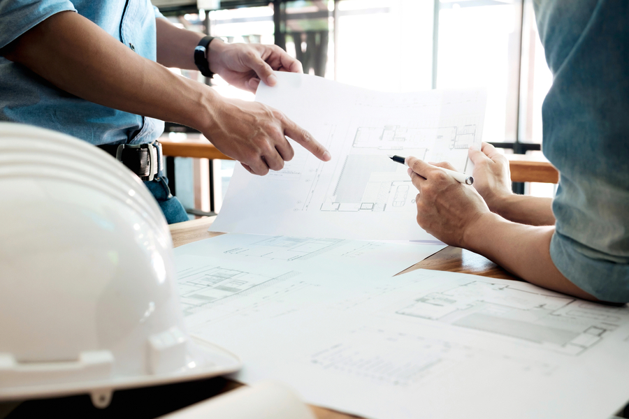 Two people reviewing home construction blueprints during a smart home planning consultation at a job site.