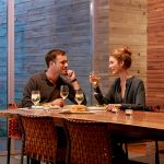 Couple enjoying dinner in a modern luxury dining room with warm ambient lighting.